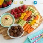 Colorful snack platter with fruit skewers, energy bites, and veggie sticks